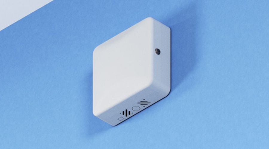 White square device mounted on a blue wall with indicator lights.