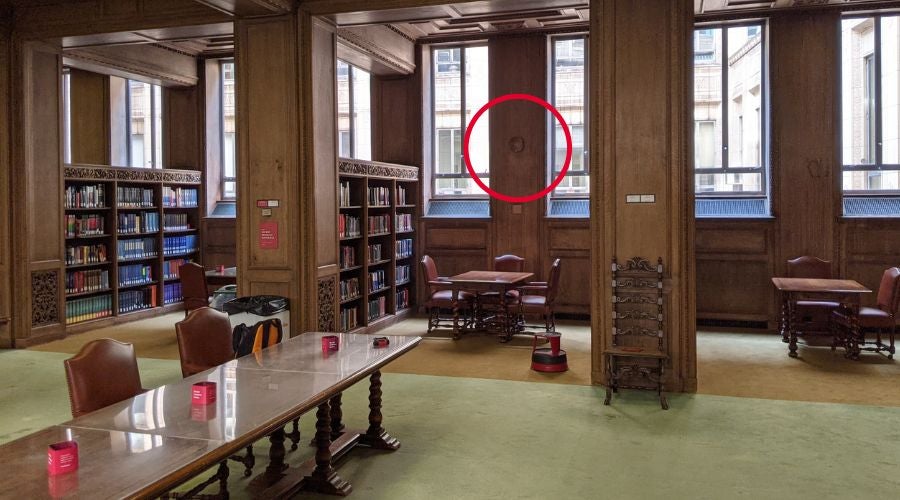 A large, historic library with a wireless access point discreetly mounted on a wooden wall, circled for visibility.