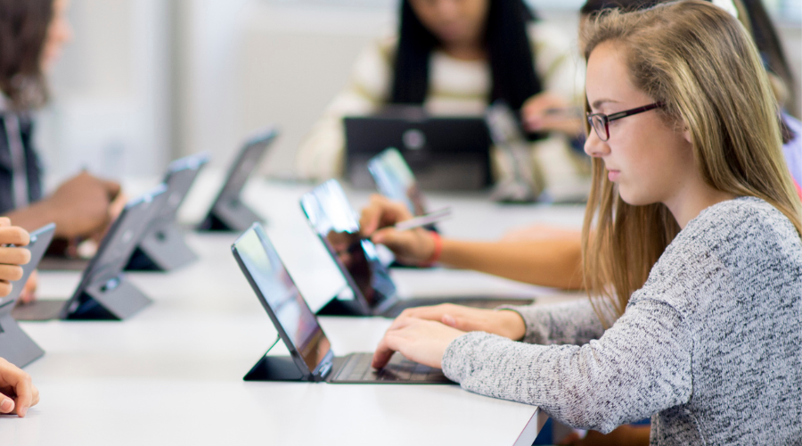 Students using tablets at a table in a classroom setting.